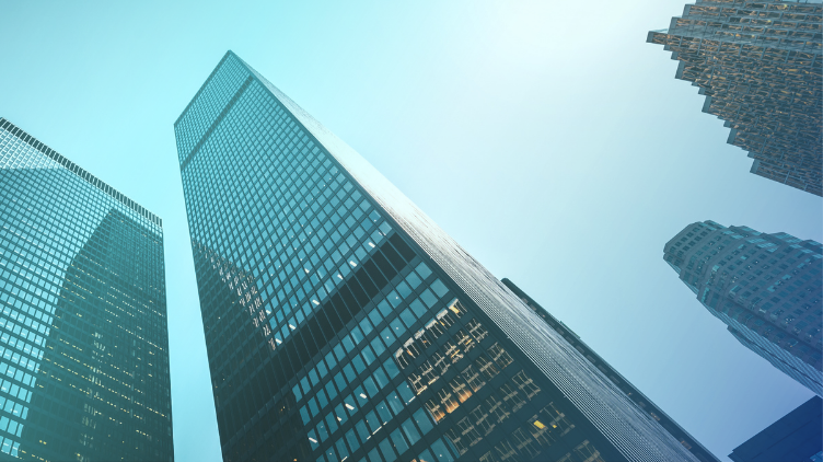Low-angle view looking up at modern skyscrapers stretching into a clear sky.
