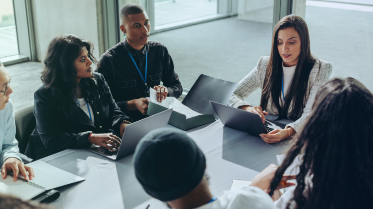 Diverse business team collaborating around a conference table with laptops and documents.